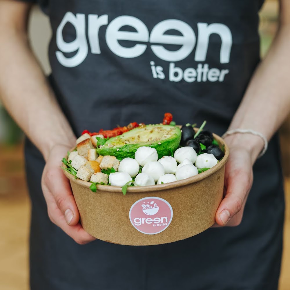 Un bol de salade Green Is Better tenu devant un tablier portant le nom de l’enseigne.