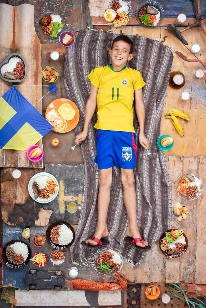 Davi en maillot jaune, entouré d’assiettes de riz, de haricots, de pâtes et de fruits.