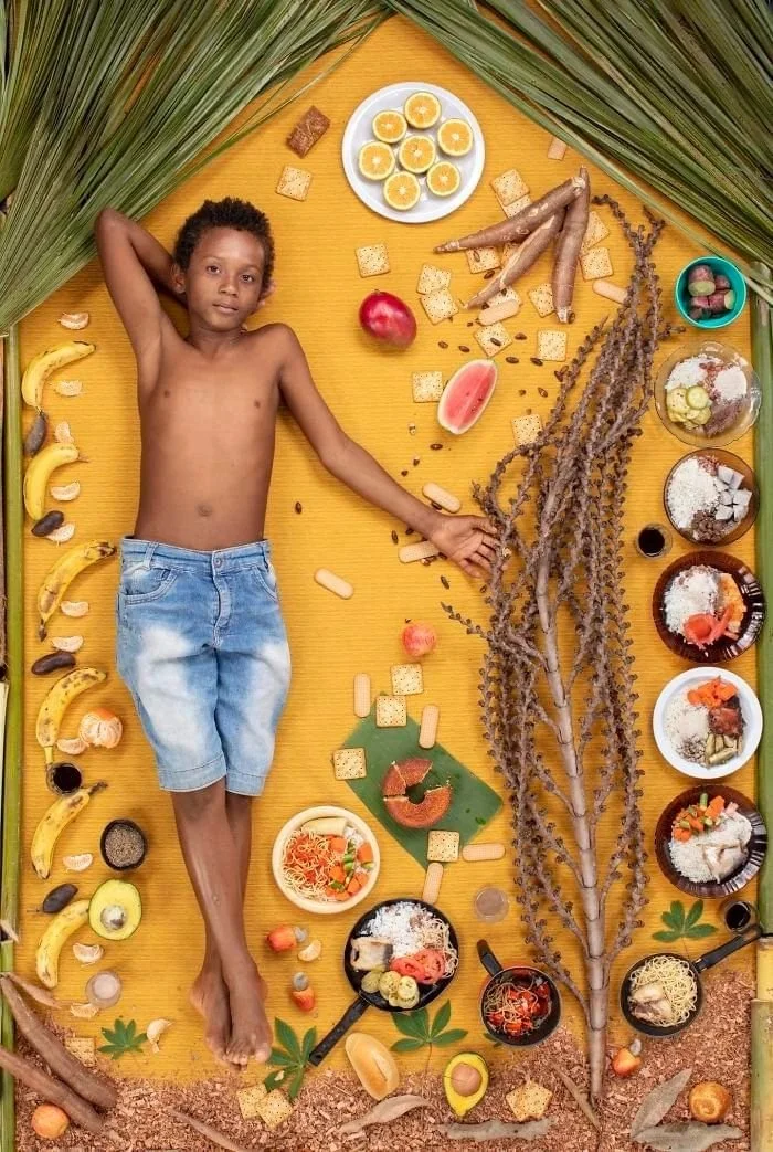 Ademilson sur un fond jaune, entouré de fruits, de racines et d’assiettes préparées.