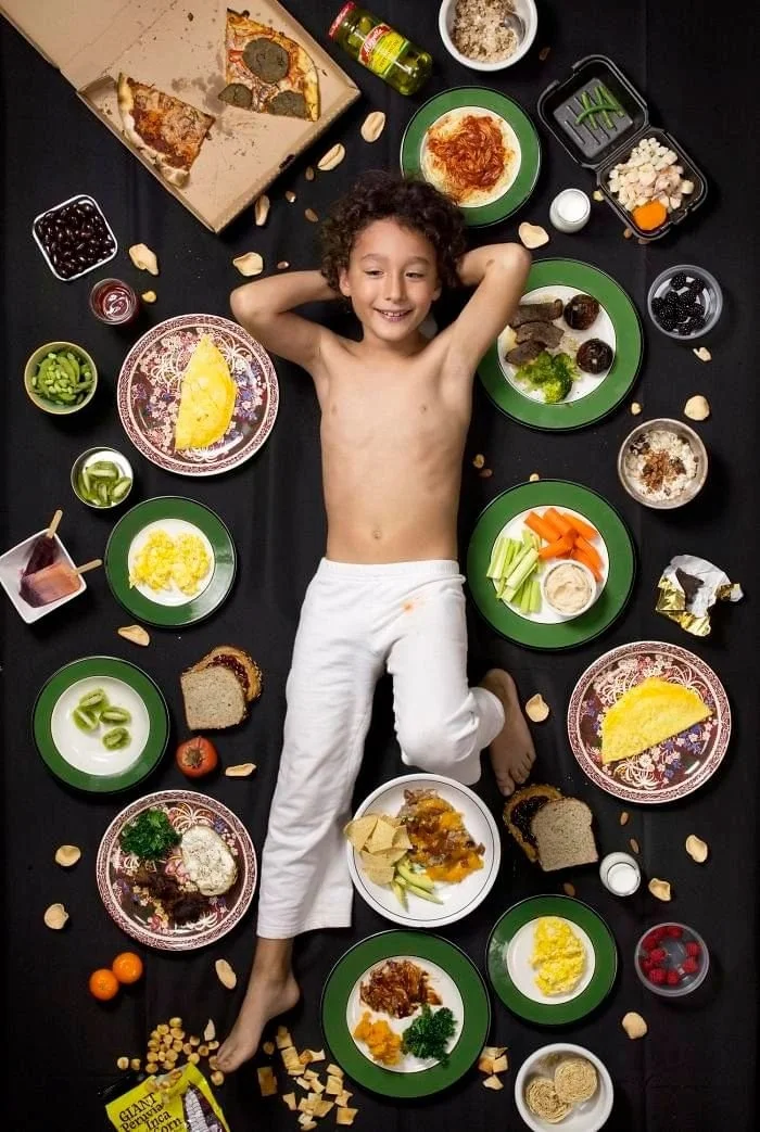 Hank sur un fond sombre, entouré de légumes découpés, de fruits et de plats variés.
