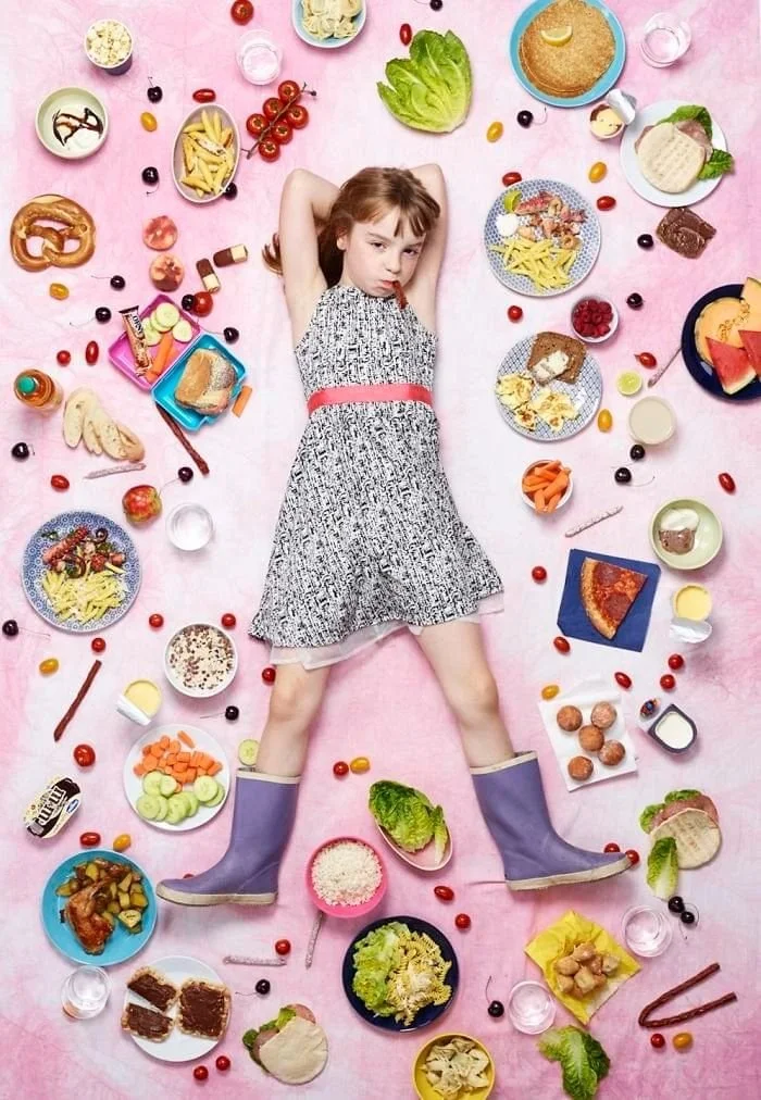 June sur un fond rose, entourée de bretzel, de légumes, de fruits et de plats.